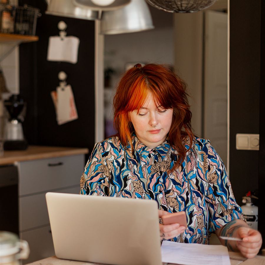 Kvinne med rødt hår sitter ved en laptop.