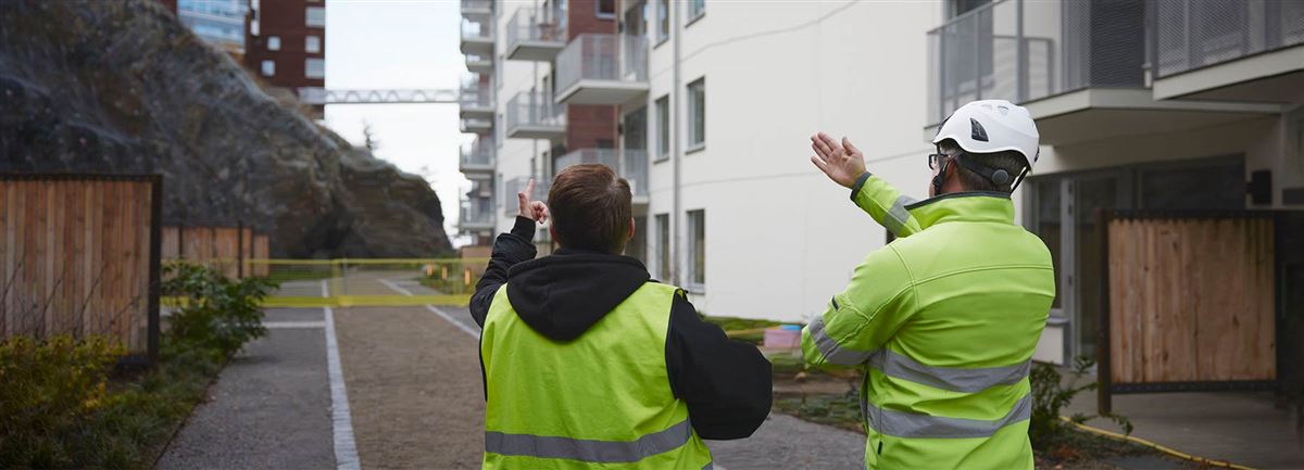 Anleggsarbeidere står med ryggen til