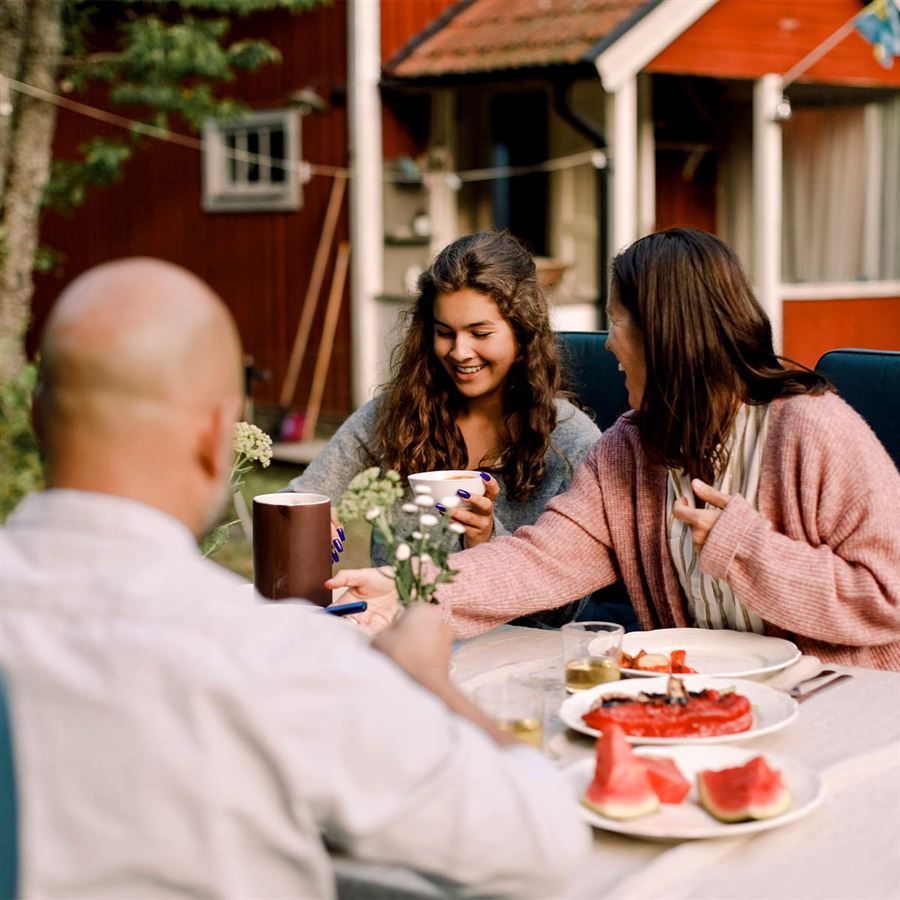 Familie drikker kaffe i hagen