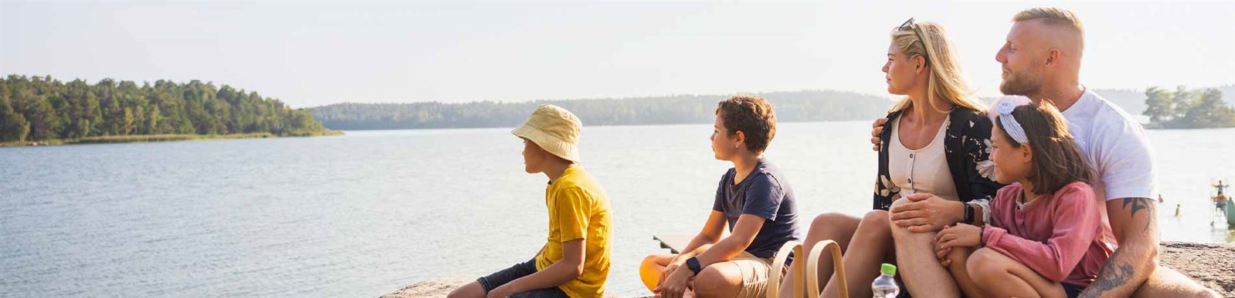 Familie sitter ved vannet