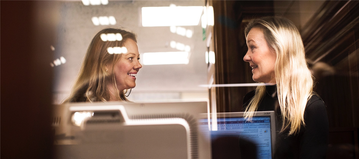To kvinner snakker sammen på et kontor
